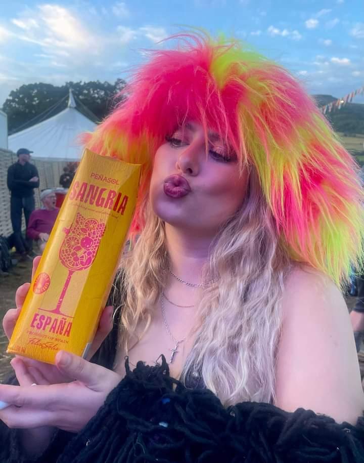 mega fluffy wide brimmed faux fur hjat in pink and yellow. worn by a girl at a festival